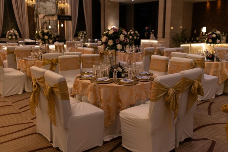 Beautifully decorated wedding reception hall with round tables and floral arrangements.